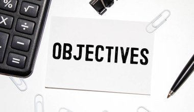Bilgisayar klavyesindeki yırtık kağıda yazılmış OBJECTIVES sözleri.