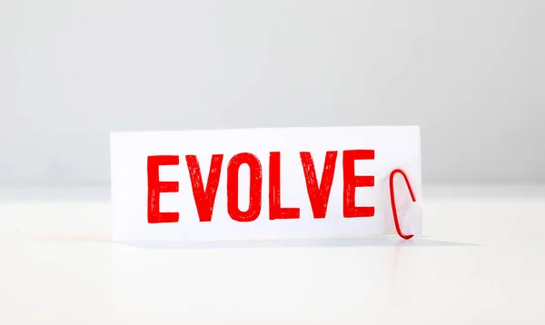 evolve. text on white notepad on documents.