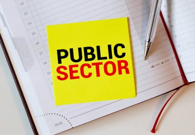 Kalemlerle birlikte bir deftere yazılmış Kamu Sektörü metni.