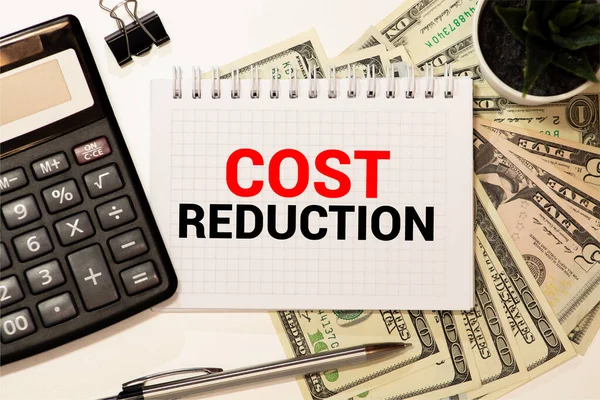 Cost Reductions words on copybook page, Production or reselling Business concept for reduction expenses for goods and services.