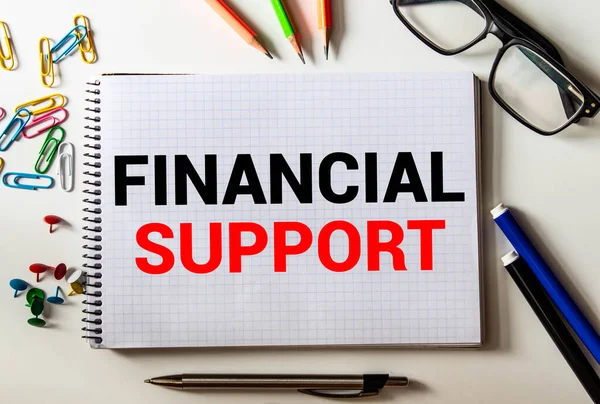 Financial Support text written on a notebook with pencils.