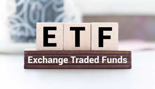 ETF, Exchange Traded Fund, realtime mutual index fund that can trade in equity stock market, cube wooden block with alphabet building the word ETF on grid line paper, random block in the background.