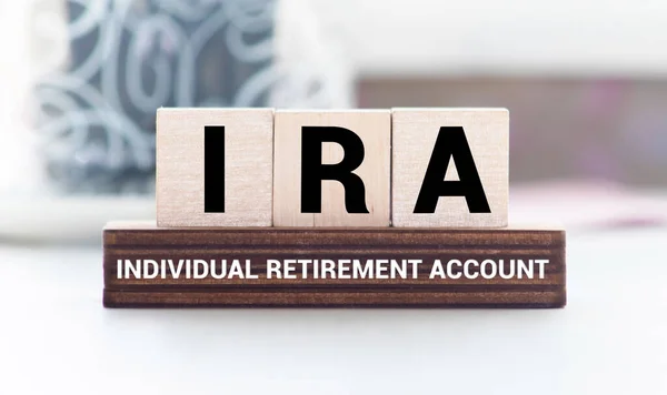 IRA individual retirement account word on wood cube block with blue background.