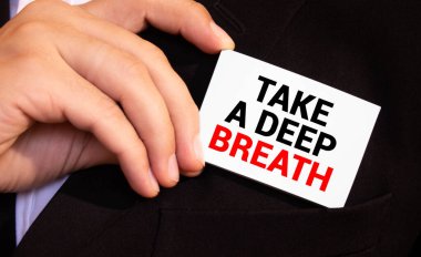 Bir iş kadını elinde bir kart tutuyor ve derin bir nefes alıyor.