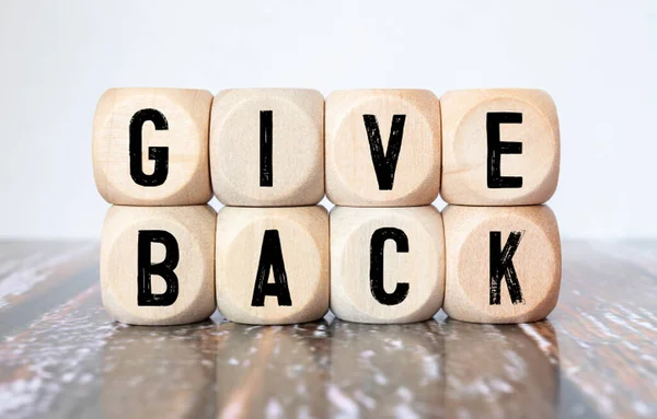 Give Back word written on wood block. Give Back text on table, concept