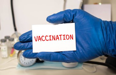 Covid-19 aşı sembolü. Mavi eldiven ve beyaz kart. 'Covid-19 aşıladı' kavramını kullan. Tıbbi ve COVID-19 aşı salgını konsepti. Boşluğu kopyala.