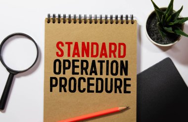 Standart İşletim Prosedürü metni kağıt üzerine açık günlükte gözlük, renkli raptiye, tahta masa üzerinde kalem ve hesap makinesi - iş ve finans kavramı