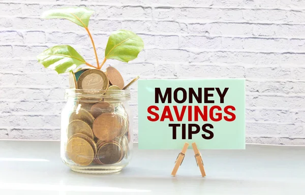 MONEY SAVINGS TIPS text with notepad, keyboard, decorative vase, fountain pen, and calculator on wooden background. Business and Copy space concept