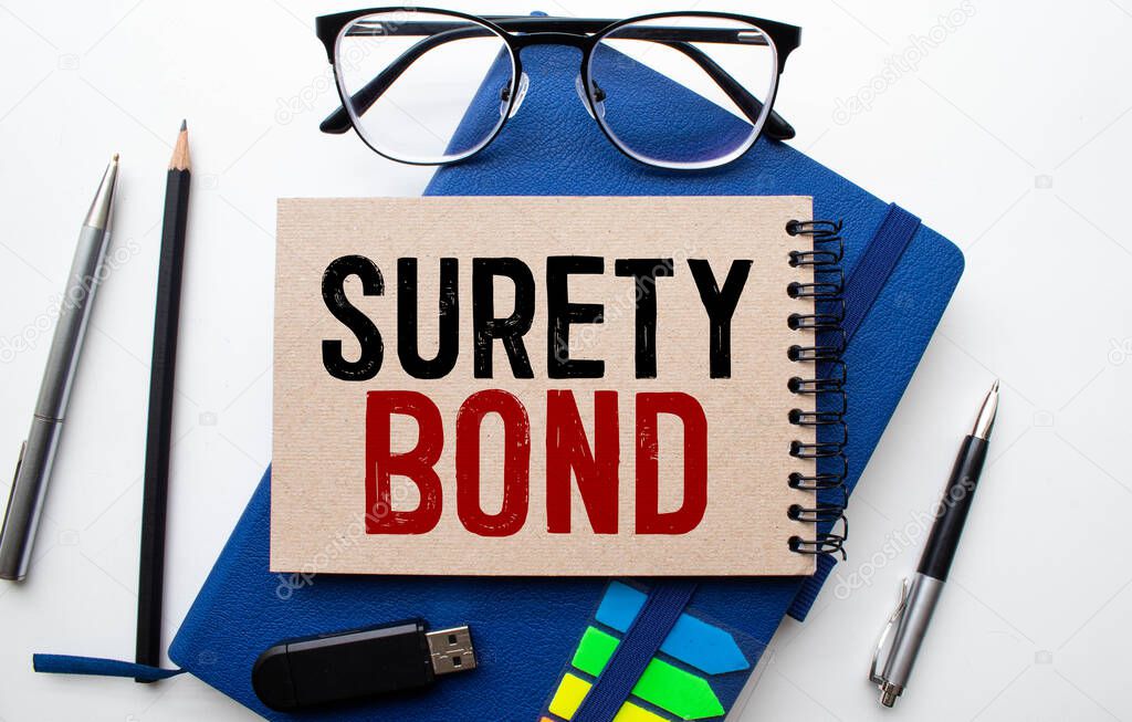 Text SURETY BOND is written on a notebook with a pen and a magnifying glass lying on the table.
