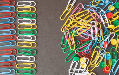 Düzen ve kaos kavramı. Kaotik düzensiz renkli ataçlar ve metal ataç siparişi.