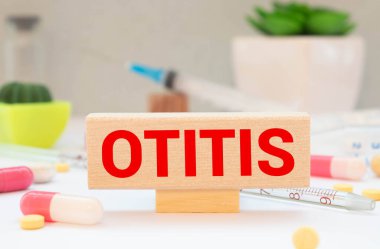 Beyaz arka planda haplı OTITIS sözcüğüyle üst görünüm blokları.