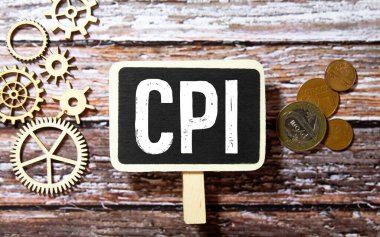 Güneş gözlüklerinin üst görüntüsü, bir fincan kahve, defter, kalem, bitki ve hesap makinesi gri zemin üzerinde CPI ile yazılmış..