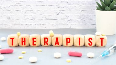 Masanın üzerinde stetoskop, not defteri, büyüteç ve üzerinde THERAPIST yazan Jenga var..