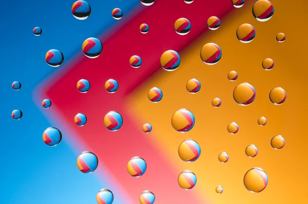 Різнокольорові краплі води на кольоровому фоні — стокове фото