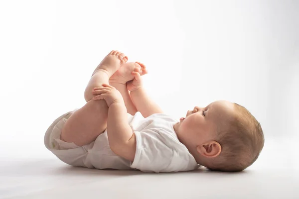 Baby Lies His Back Holding His Legs White Background — Stock Photo, Image