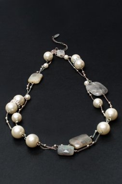 Siyah bir zemin üzerine taş ve inci kolye