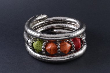 iron bracelet with colored stones isolated on black clipart