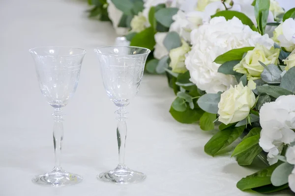 Glasses of the bride and groom on the background of flowers — Stock Photo, Image