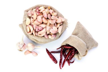 Sarımsak. Torbada taze sarımsak ve kurutulmuş biber. Beyaz arkaplana yerleştirilmiş - üst görünüm