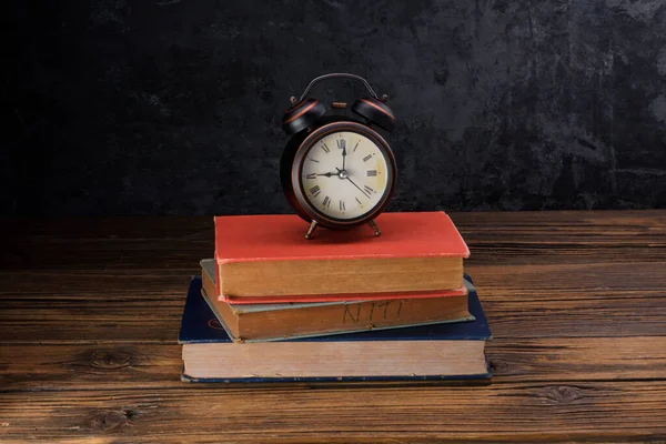 Wecker Auf Alten Büchern Auf Altem Holztisch Platziert Schwarzer Wandhintergrund — Stockfoto