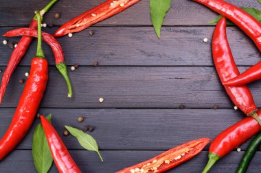 Koyu renkli ahşap masa manzaralı kırmızı biber ve kırmızı biber.