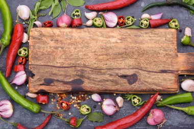 Kırmızı biber, fesleğen, sarımsaklı biber ve siyah ahşap masaya yerleştirilmiş baharatlar.