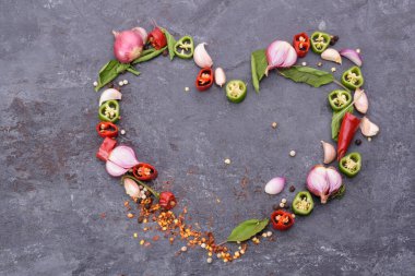 Kırmızı biber, fesleğen, sarımsak, biber ve baharatlar siyah ahşap bir masa üzerine kalp şeklinde yerleştirilmiş mesaj yazmak için boş bir alan var.