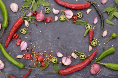 Kırmızı biber, fesleğen, sarımsaklı biber ve baharatlar siyah ahşap bir masaya konmuş mesaj yazmak için boş bir alan var.
