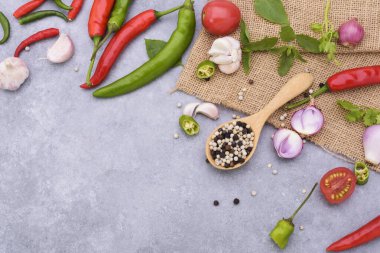 Ahşap kaşıkta biber ve kırmızı biber soğanlı sarımsaklı fesleğen, kişniş yaprağı ve domatesler masanın üstüne..