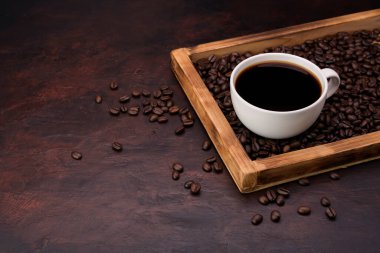 Siyah kahve fincanı. İğne renkli masanın üstünde kavrulmuş kahve çekirdekleri var. Üstünde fotokopi alanı olan üst manzara.