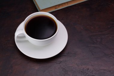 Kahve fincanı beyaz çay tabağıyla masaya koyu siyah bir kahve koy eski kitaplarla - fotokopi alanının olduğu üst manzara.