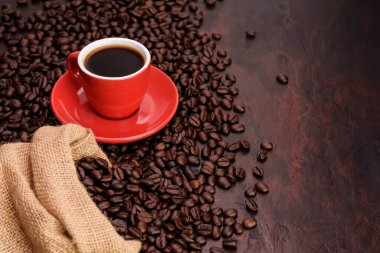 Siyah iğneli kırmızı kahve fincanı çay tabağı ve kokulu kahve çekirdekleri iğne renkli masada - fotokopi alanı ile üst manzara.