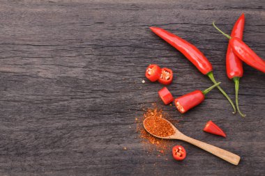 Kaşıkta kırmızı biber ve eski bir ahşap masada bir demet kırmızı biber.