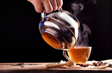 Çay seremonisi çay seremonisi taze demlenmiş bir fincan siyah çay ahşap bir masaya konur ılık, yumuşak bir ışığın siyah bir arka plana doğru parladığı yere..