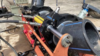 Tesisatçı, fabrikadaki boruları bağlamak için hidrolik bir PE kaynak makinesiyle tesisat üzerinde çalışıyor..