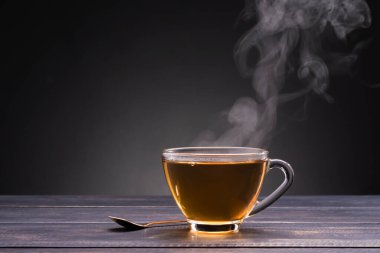 organik sıcak çay, siyah arka plandaki ahşap bir masaya konur.