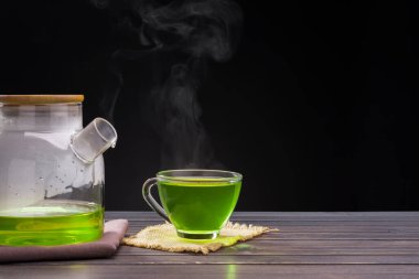 Organik taze yeşil çay, siyah arka plandaki ahşap masaya konulmuş.