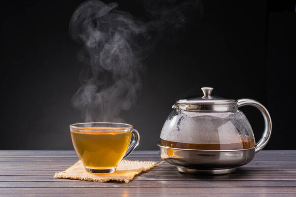 organic hot tea placed on a wooden table on a black background