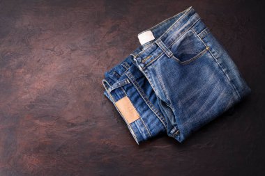 Koyu renkli ahşap bir masada yatan mavi kot pantolon. Modern moda kotları - metin kopyalamak için alanı olan üst görünüm.