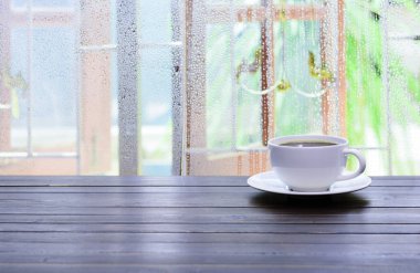 Pencerenin yanındaki masaya beyaz bir fincan kahve konur..