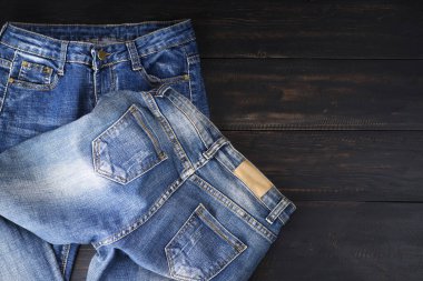 Koyu siyah ahşap bir masada dinlenen mavi kot pantolon. Modern moda kotları - metin kopyalamak için alanı olan üst görünüm.