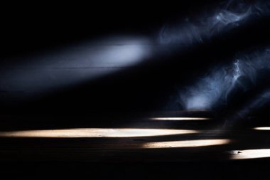 Eski kahverengi ahşap zemin ya da arkasından siyah ve koyu arkaplanda ışık gelen boş bir masa..