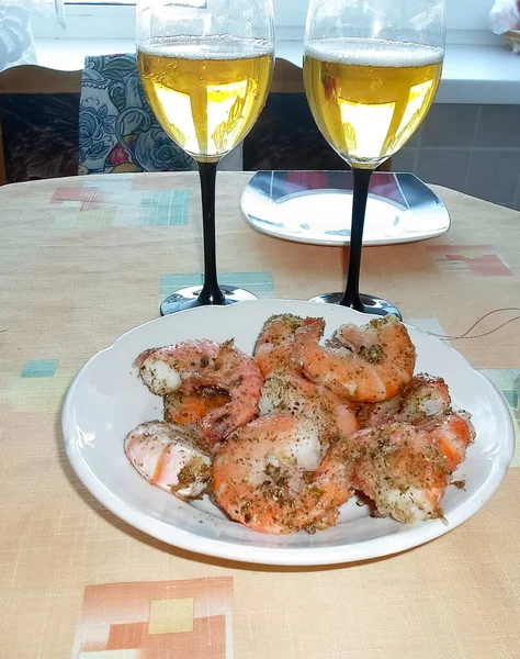 Crevettes cuites avec du poivre sur une assiette. Versé 2 verres de vin blanc — Photo