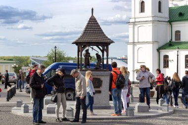İnsanlar anıtın ve tapınağın yanındaki meydanda duruyorlar.