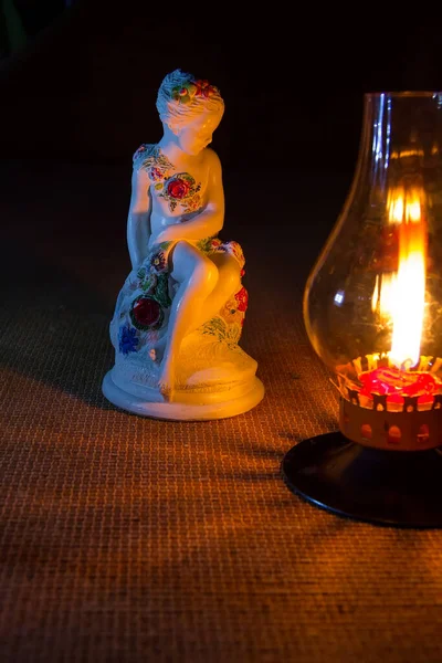 Égő gyertya és szobor egy lány éjjel lámpával — Stock Fotó