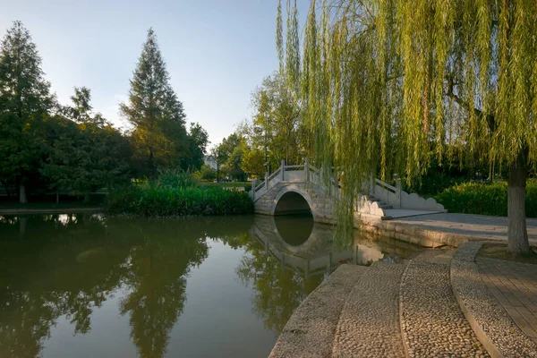 Стежка в парку з ліхтарем і лавкою і мостом — стокове фото