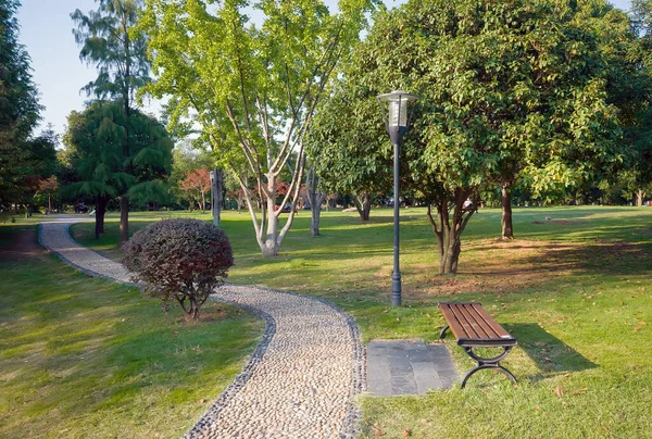 Camino en el parque con una linterna y un banco — Foto de Stock