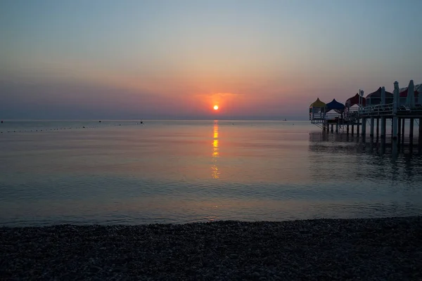 Reflejo del sol en el mar por la mañana, cerca del muelle — Foto de Stock