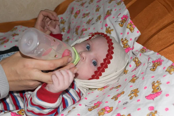 Маленька дитина лежить на ліжку і годується пляшкою — стокове фото