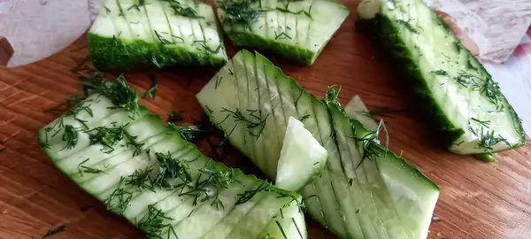 Fresh cucumbers cut and sprinkled with dill and salt — Stock Photo, Image